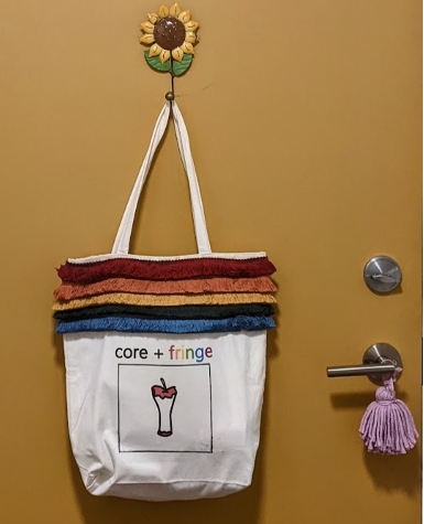a bag with an apple core and the words “core + fringe” and red, orange, yellow, green, and blue fringe