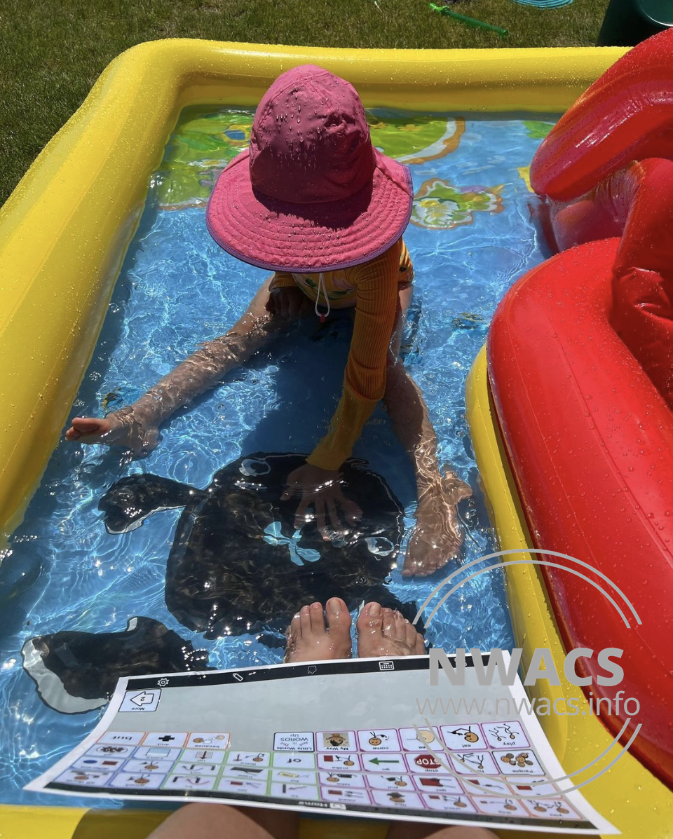 Melissa's daughter in an inflatable pool with a printed communication page visible