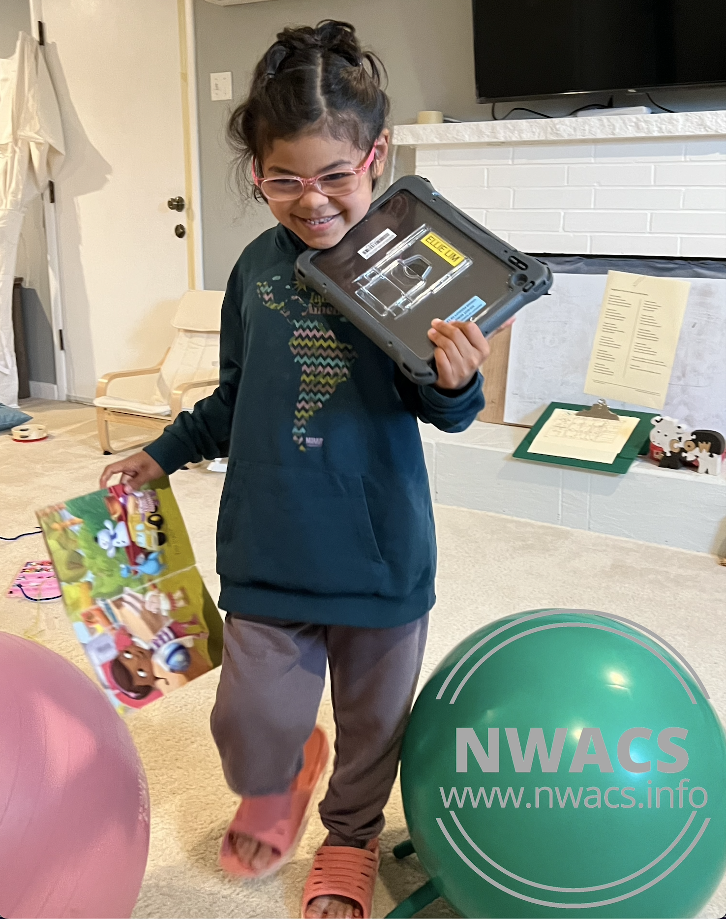 Melissa's daughter carrying a book and her AAC device across a room.