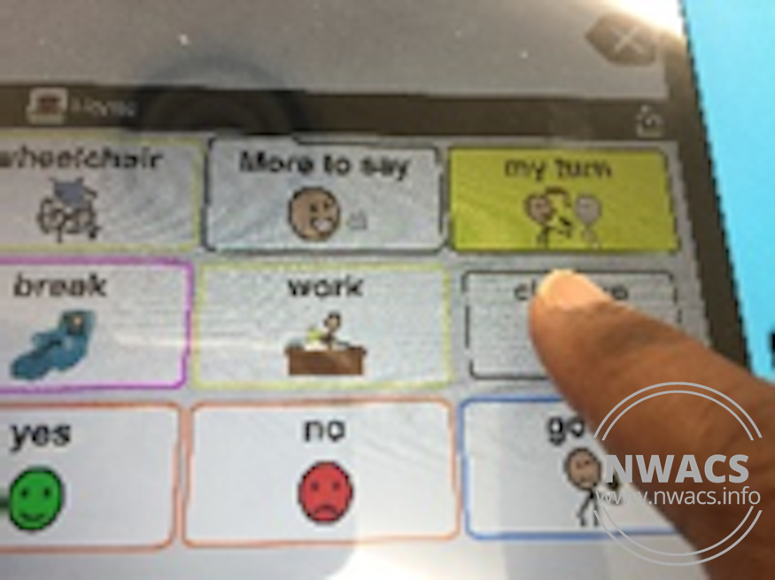 finger touching a button on an AAC device screen